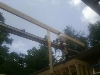 Carpenter setting a ridge beam over a new addition frame — Ice Dam Removal by Roofing Brothers in Clymer