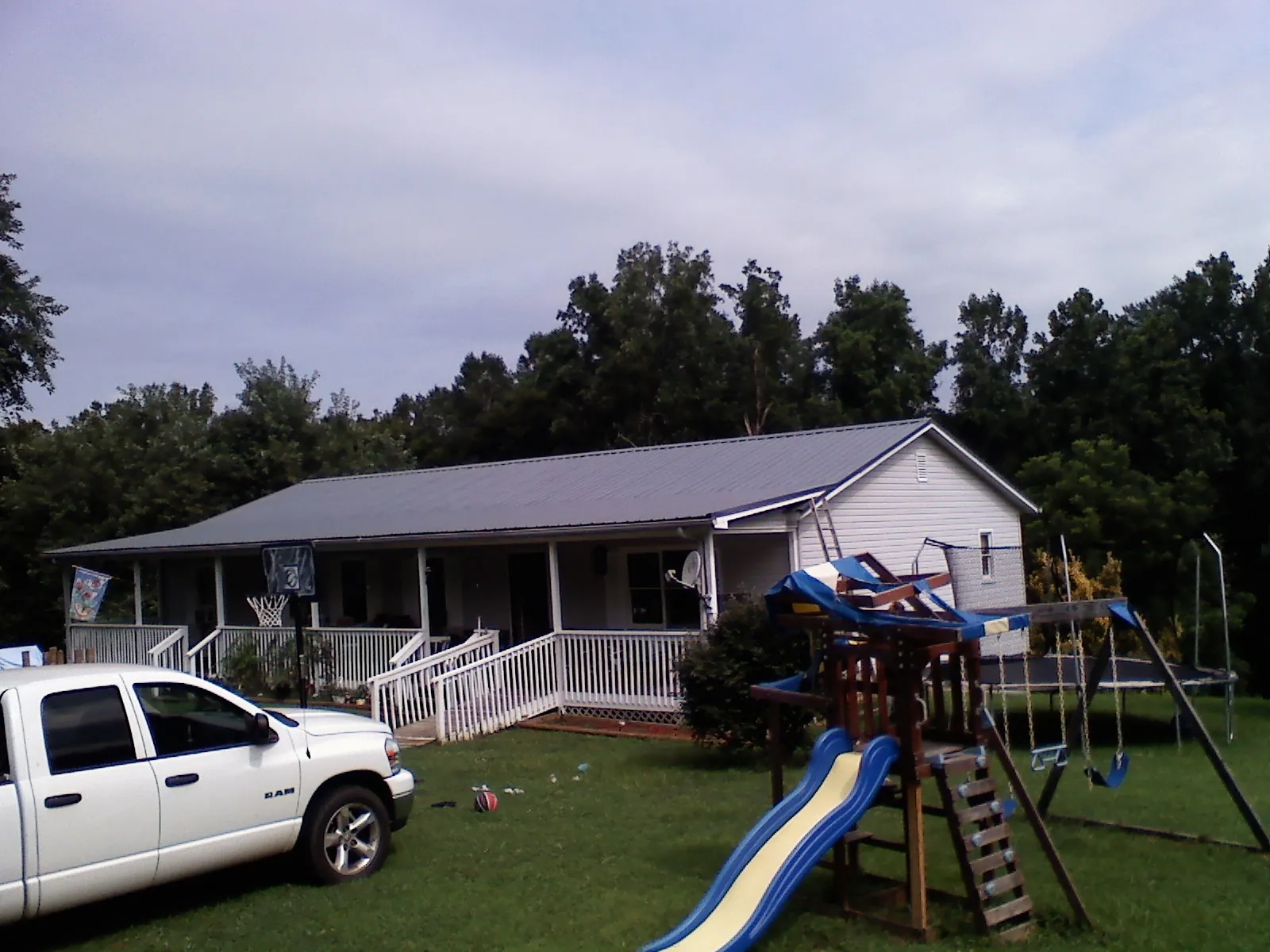 Dark metal roof on a country home with a full length front porch in Clymer