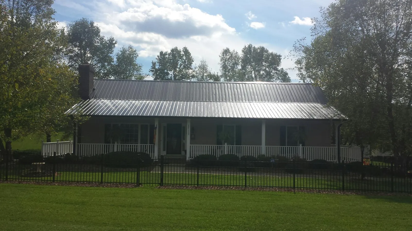 Gray metal roof on a brick ranch with a full width front porch — Gutter Guard Installation work by our crew in Clymer