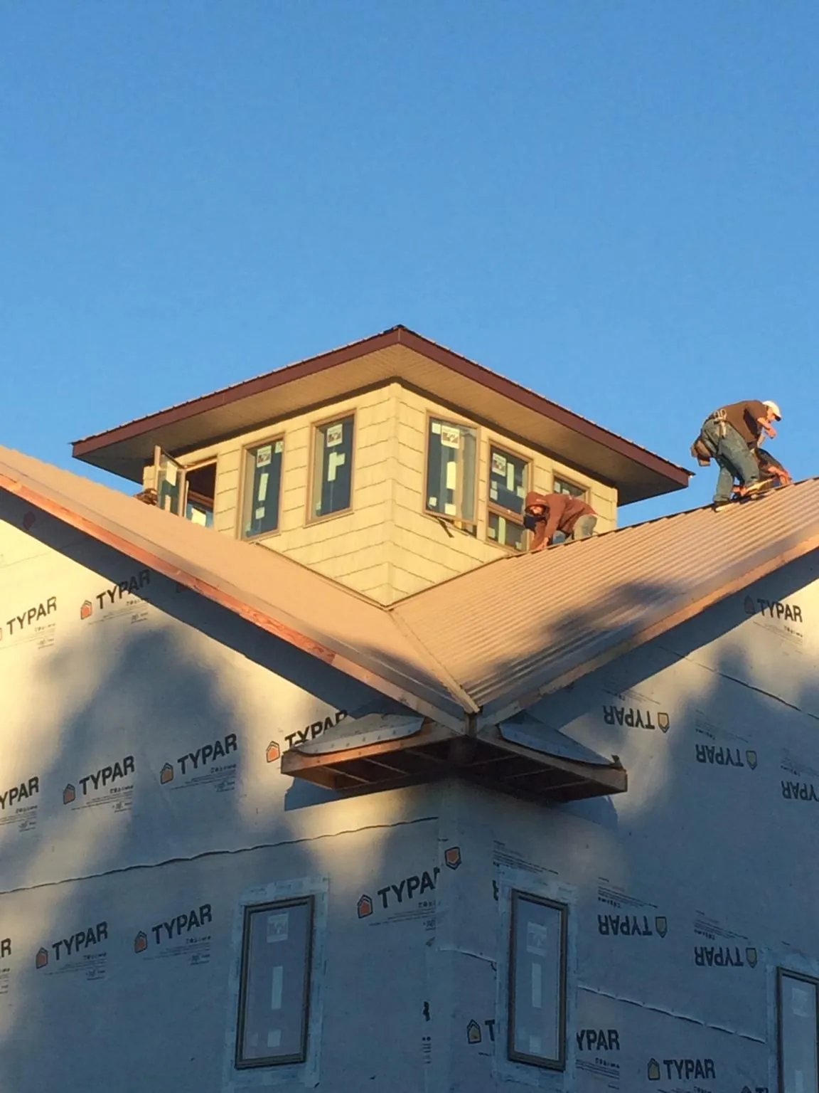 Roofers working around a rooftop cupola on a new metal roof at sunset — Roof Waterproofing in Clymer by Roofing Brothers